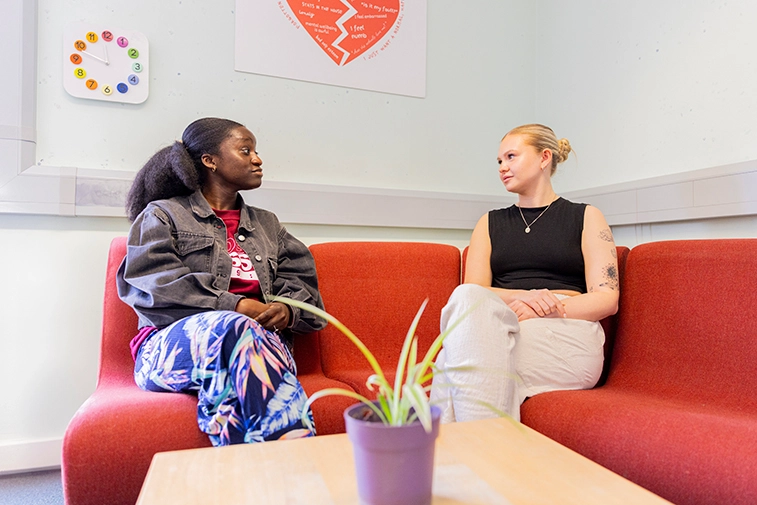 Two people having a conversation on a sofa.
