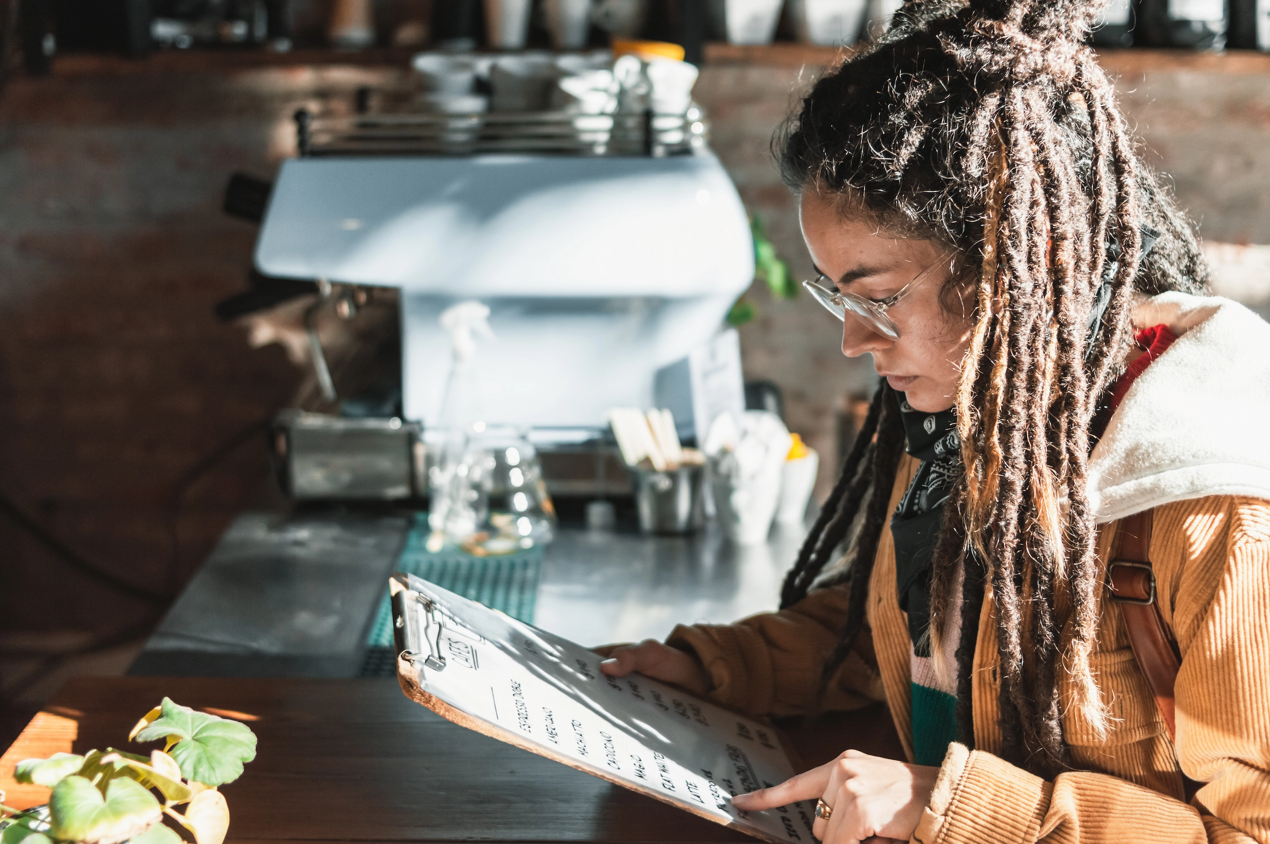 Young woman with dreadlocks reading the menu.